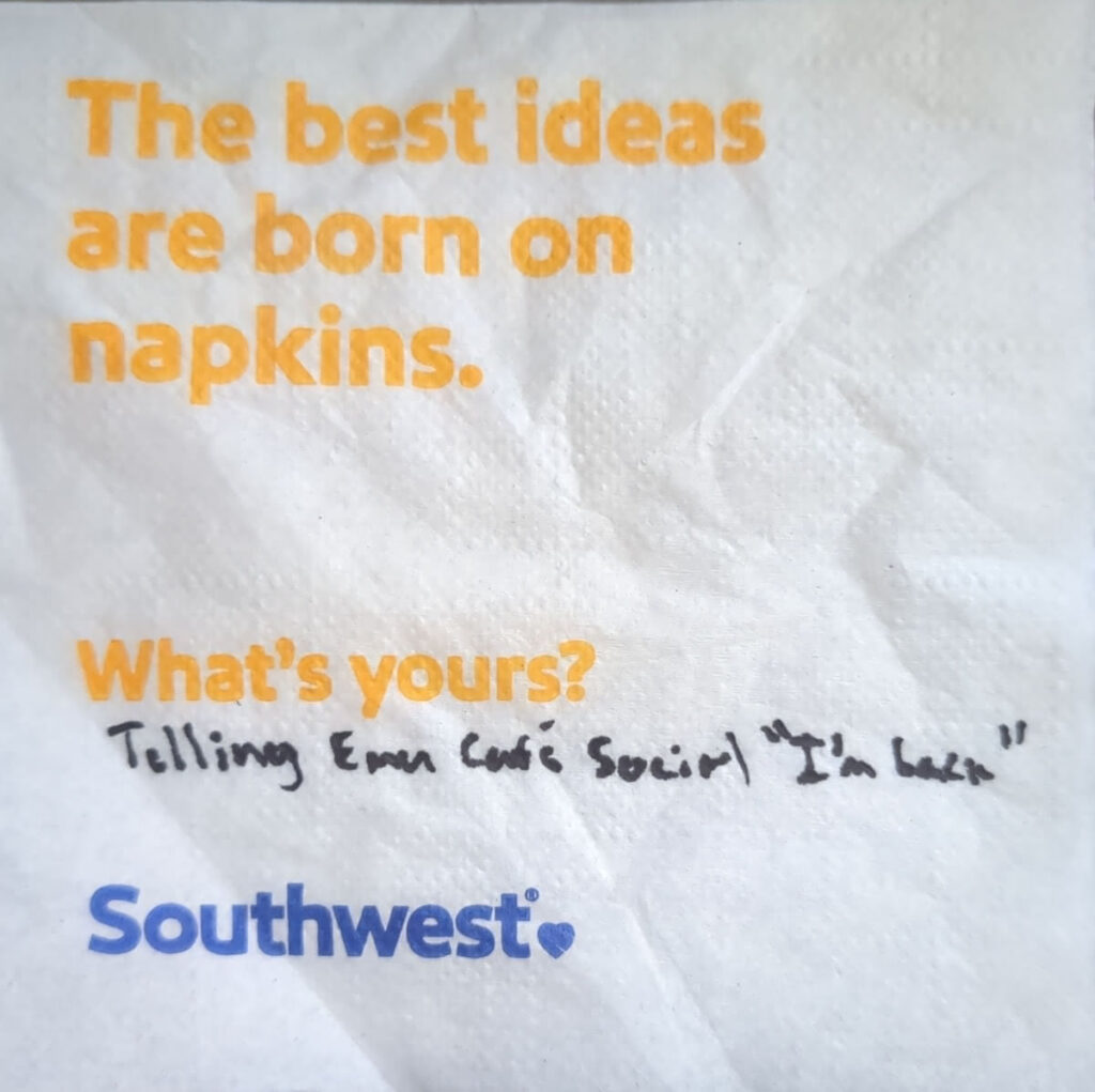 A Southwest Airlines napkin. The top says in orange text "The best ideas are born on napkins" and below "What's yours?" In black ink, I wrote "Telling Emu Cafe Social 'I'm back."